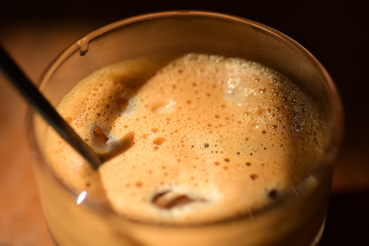 about-01 Inviting close-up of frothy iced coffee in a glass with a straw, perfect for refreshing moments.