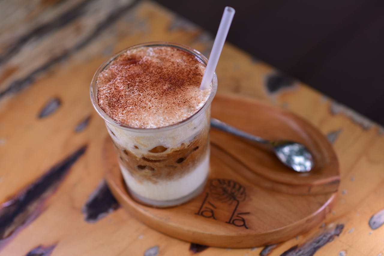 services-01 Close-up of iced coffee with cream and cinnamon on a wooden tray, perfect for coffee enthusiasts.
